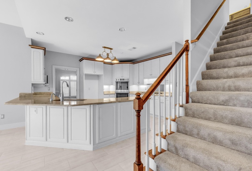 Carpeted staircase with wood banister and white spindles