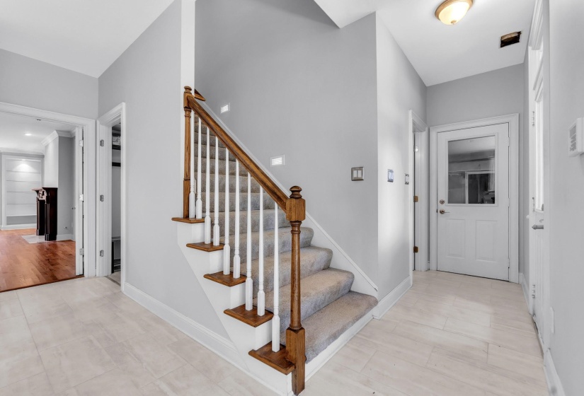 Foyer featuring a hardwood and white spindle staircase with carpeted treads