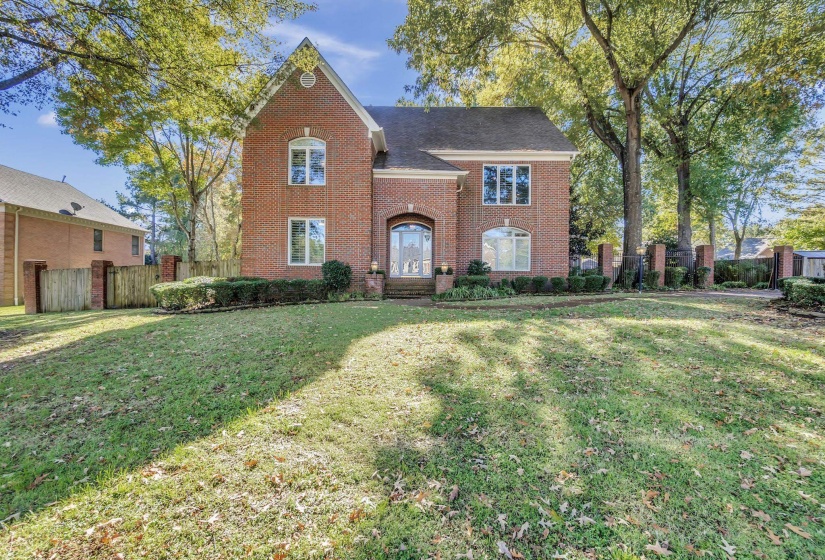 Red brick exterior with white trim windows and an arched glass entry door