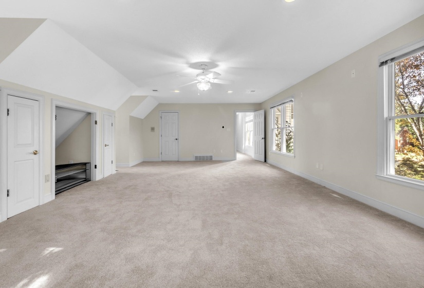 Spacious room featuring neutral carpet, multiple windows, recessed lighting, and a ceiling fan
