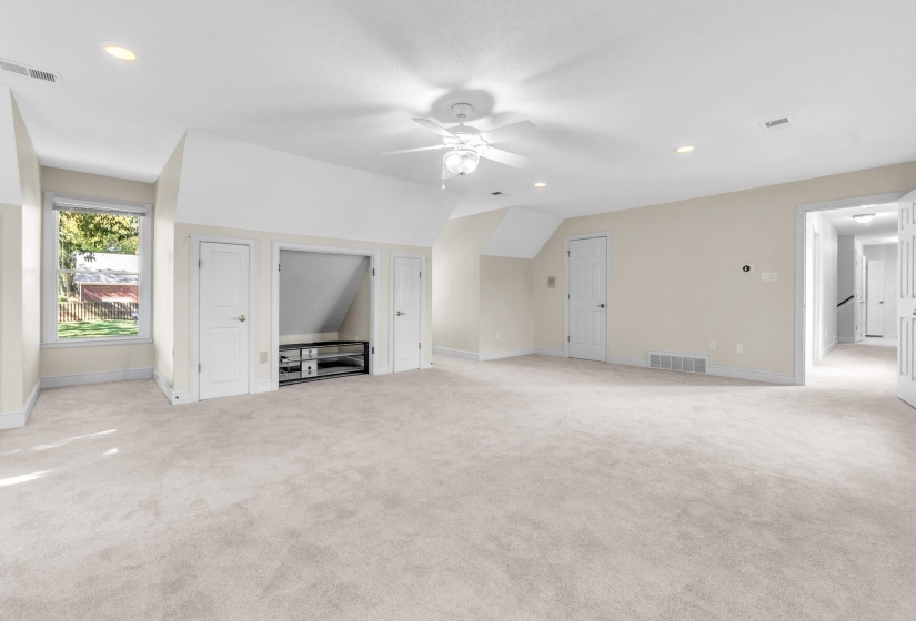 Spacious room featuring neutral carpeting, recessed lighting, and a ceiling fan
