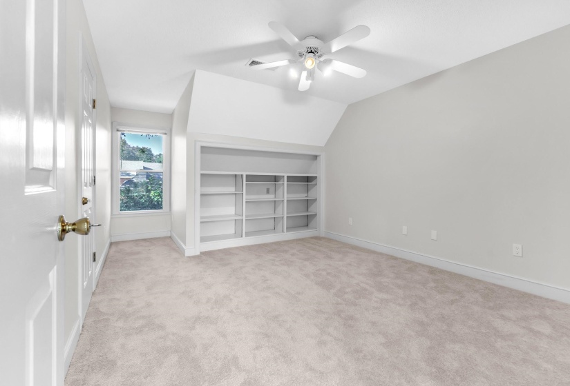 Carpeted room featuring a built-in bookcase, recessed window, and ceiling fan with integrated lighting