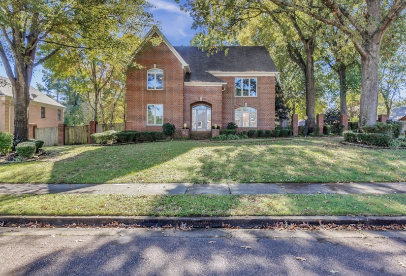 Brick two-story residence featuring a gabled roofline and arched entryway