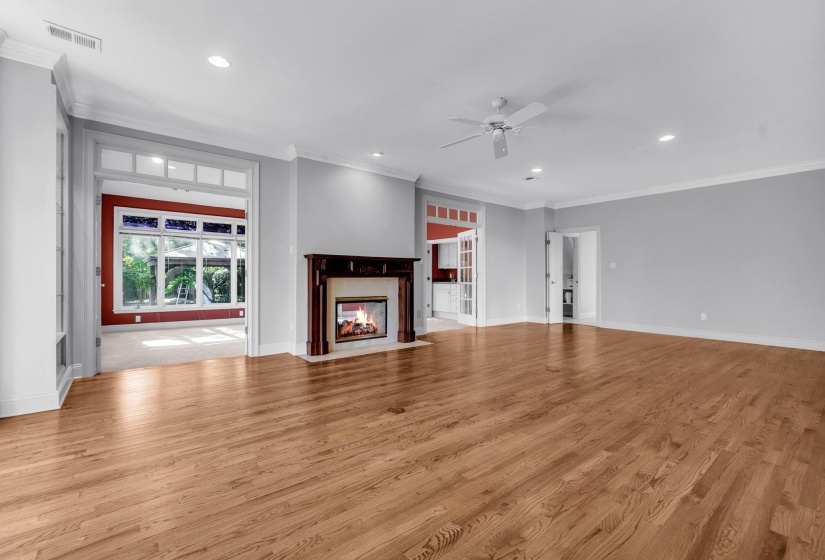 Spacious interior room featuring wood-finish flooring, a decorative fireplace with a dark wood mantel, recessed lighting, and a ceiling fan