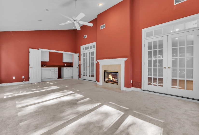 Spacious room featuring vaulted ceilings, a ceiling fan, and light-toned carpeting