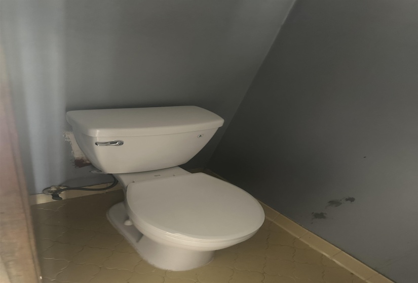 White porcelain toilet with a chrome flush lever, set against gray walls