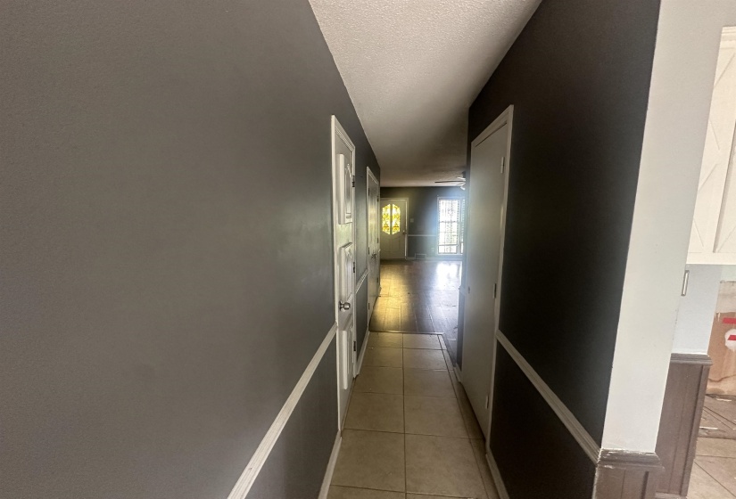 Hallway featuring neutral-toned walls, tile flooring, and multiple doorways