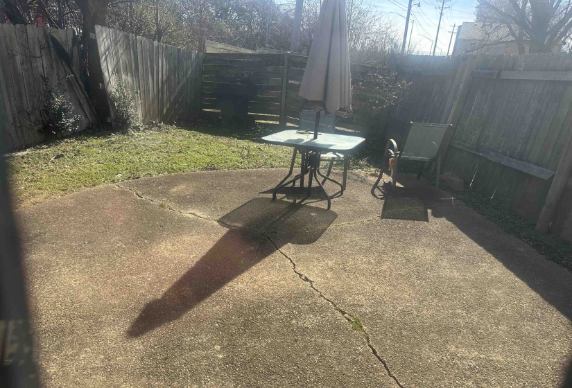 Concrete patio area bordered by a wooden privacy fence, featuring a grassy expanse