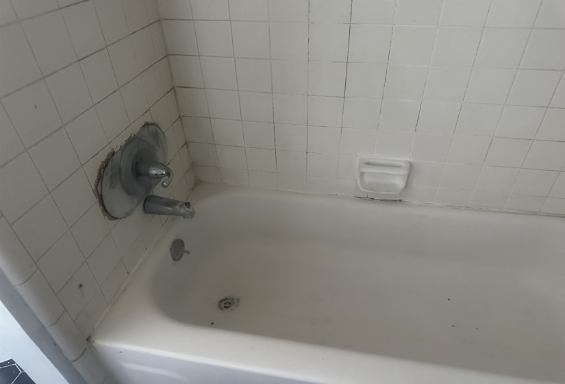 White tiled shower surround with an integrated soap dish and chrome fixtures