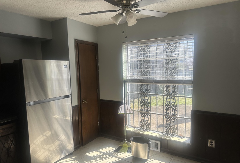Kitchen area featuring a contemporary stainless-steel refrigerator, a multi-pane window with horizontal blinds, and dark wood wainscoting