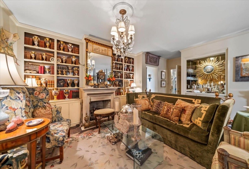Living area with crown molding, a chandelier, and a fireplace