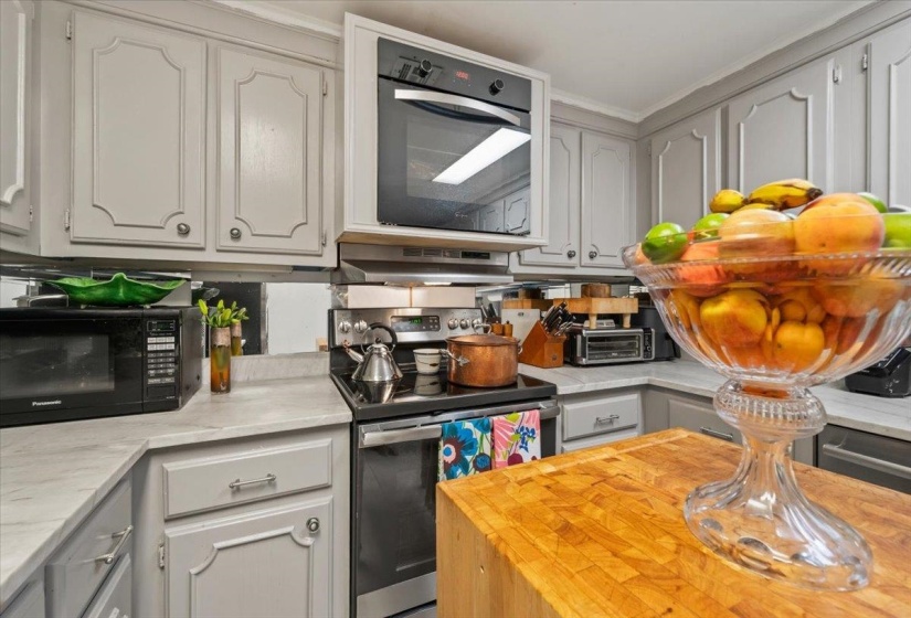 Kitchen featuring stainless steel electric range, black microwave, butcher block counters, crown molding, and gray cabinetry