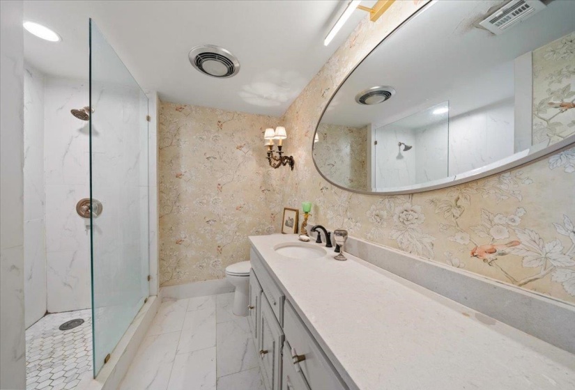 Bathroom featuring a marble finish shower, vanity, wallpapered walls, and marble finish flooring