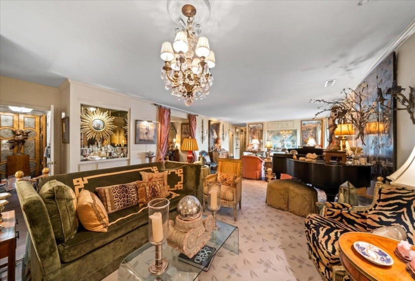 Living room with light colored carpet, a chandelier, and ornamental molding