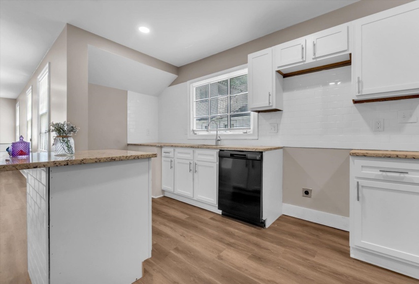 Kitchen featuring white cabinetry, granite-style countertops, wood-finish flooring, a white subway tile backsplash, and a built-in black dishwasher