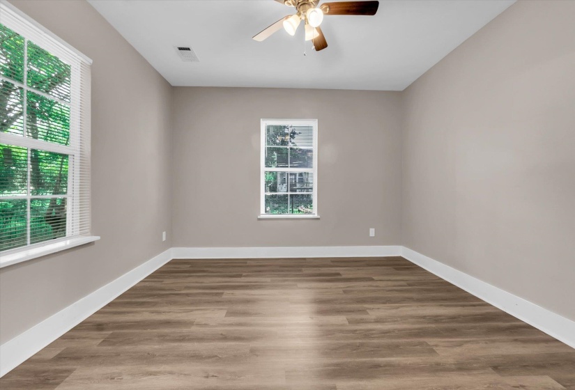 Spacious room featuring wood-finish flooring, neutral-toned walls, and white baseboards