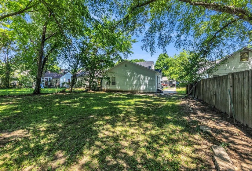 Expansive backyard with a manicured lawn, established trees, and a privacy fence