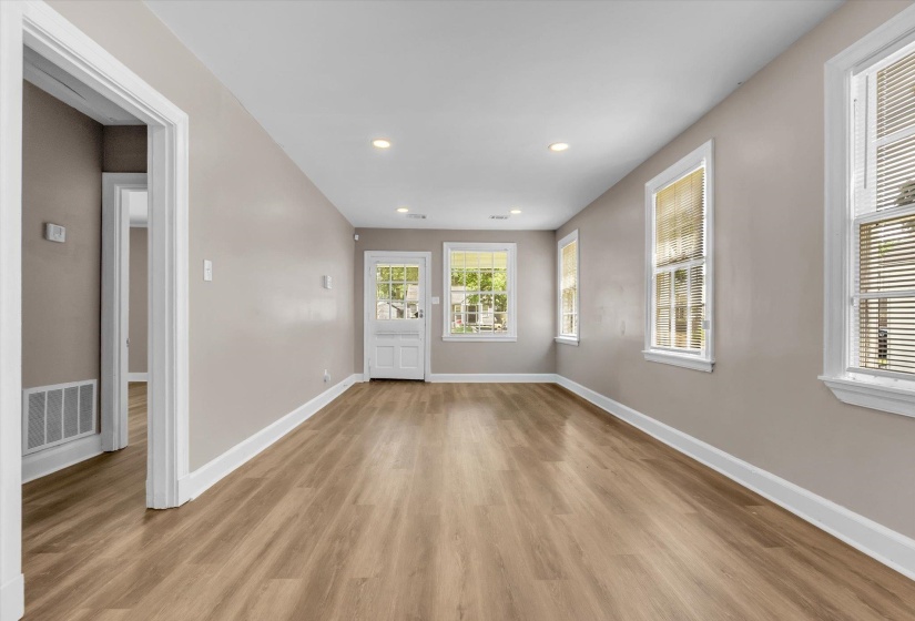 Spacious room featuring wood-finish flooring, recessed lighting, neutral wall tones, multiple windows with blinds, and white trim throughout