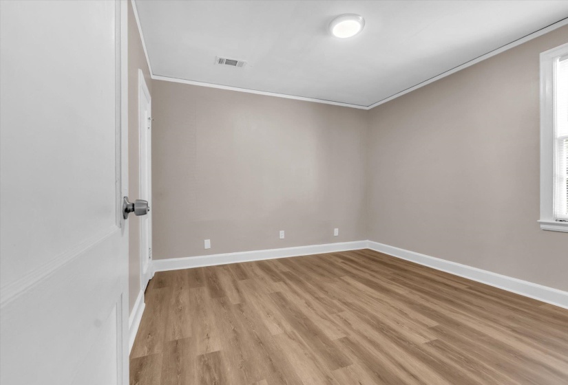Room featuring wood-finish flooring, neutral wall tones, white trim, a flush-mount ceiling light, and a window with blinds