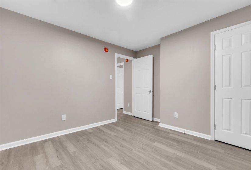 Room featuring light gray walls, wood-finish flooring, white trim, and white paneled doors