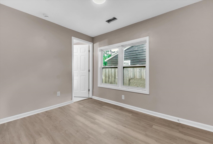 Room featuring neutral wall paint, wood-finish flooring, and white trim