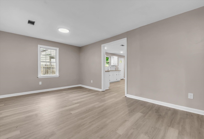 Spacious room featuring wood-finish flooring, neutral-toned walls, and white baseboards