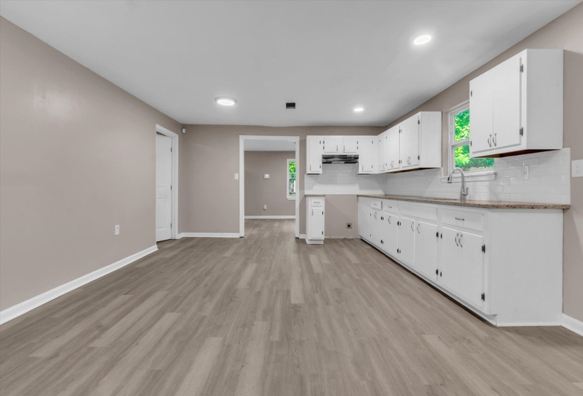 Kitchen featuring white cabinetry, light-toned countertops, white subway tile backsplash, and a stainless steel sink with a gooseneck faucet