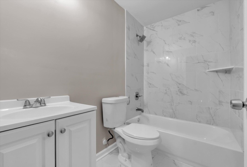 Bathroom featuring a white vanity with dual cabinet doors, a drop-in sink with a chrome faucet, and a toilet