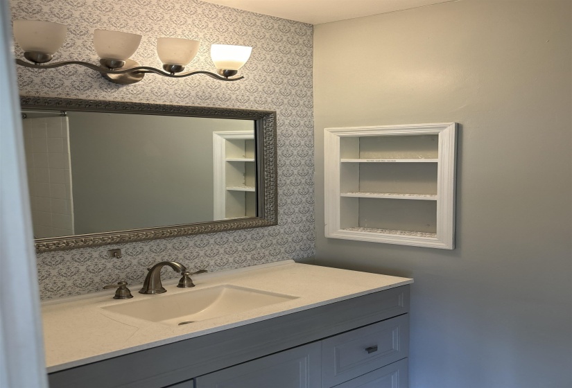 Bathroom vanity with light grey cabinetry, a light-toned countertop, and an integrated sink