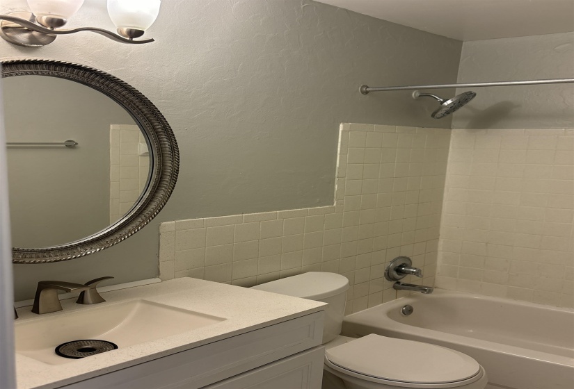 Bathroom featuring a white vanity with an integrated sink, brushed nickel faucet, and a large oval mirror