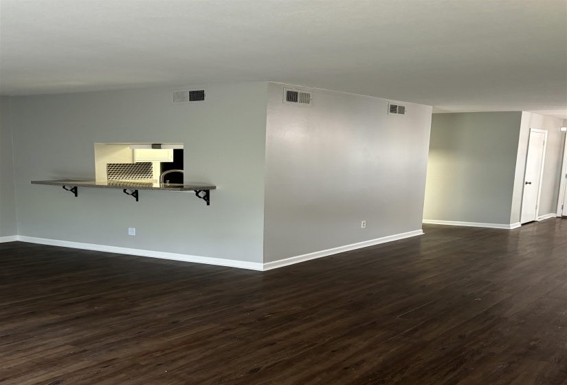 Pass-through opening to the kitchen featuring a dark stone countertop with wrought iron corbels