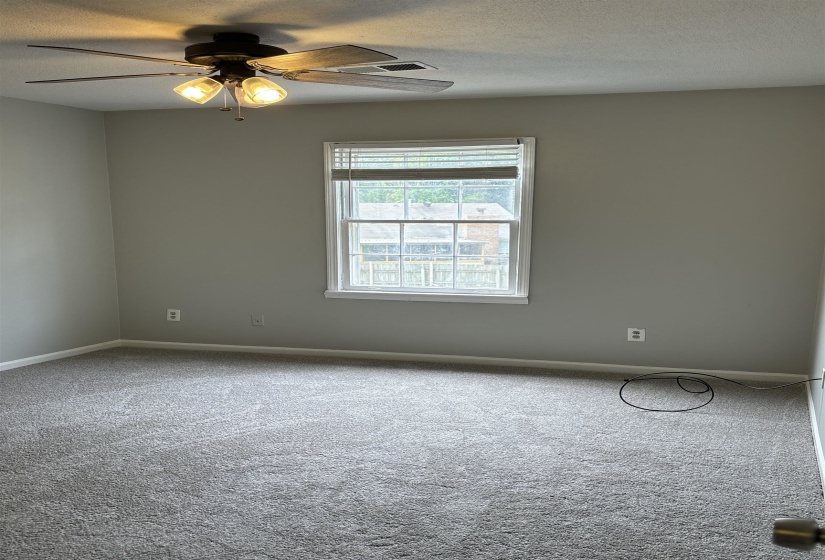 Carpeted room featuring a ceiling fan with integrated lighting, window with blinds, and neutral wall paint