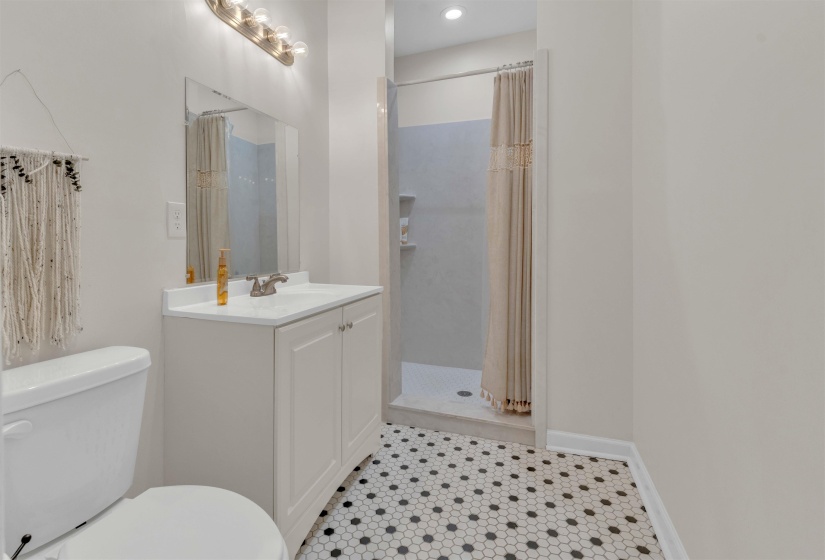 Bathroom featuring a white vanity with integrated sink, chrome faucet, wall-mounted mirror, and a five-bulb vanity light fixture