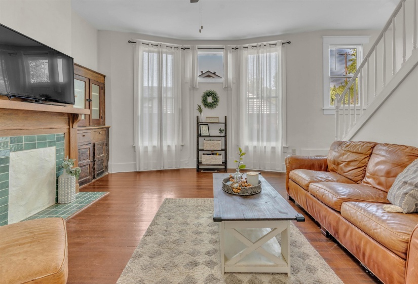 Hardwood flooring complements a fireplace with green tile surround and a built-in wooden hutch