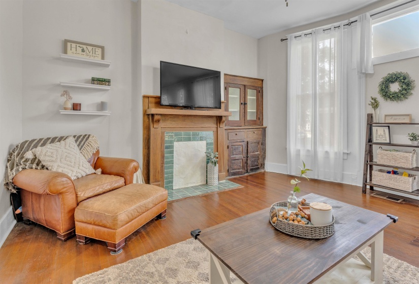 Hardwood-style flooring throughout, featuring a fireplace with decorative tile surround and an integrated wooden mantel