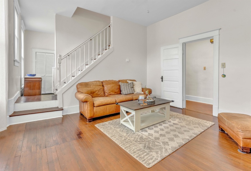 Hardwood flooring throughout, white painted staircase with balusters, and a paneled interior door
