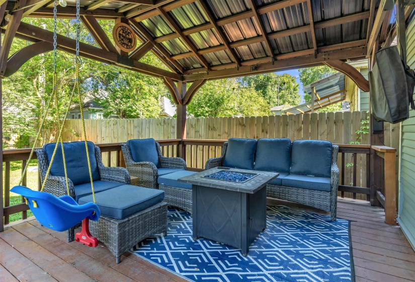 Covered wooden deck featuring a metal roof, wood railings, and a privacy fence