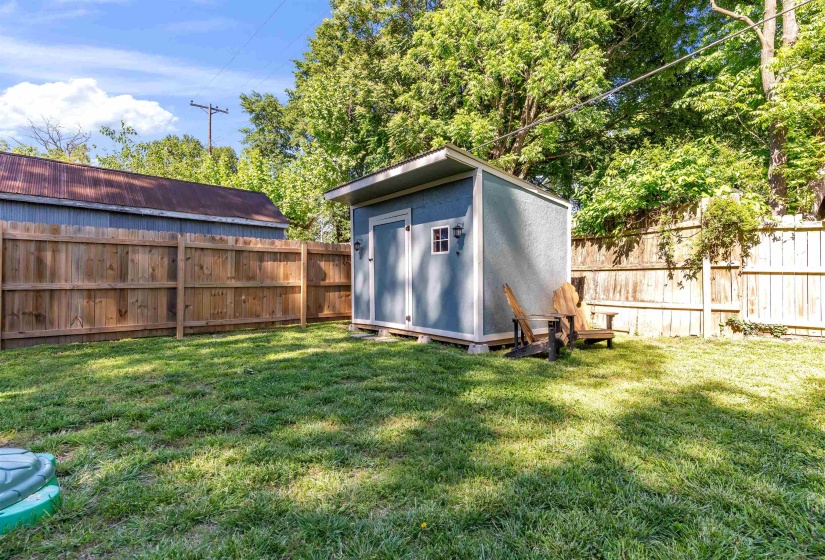 Private backyard with a detached storage shed featuring double doors and a window