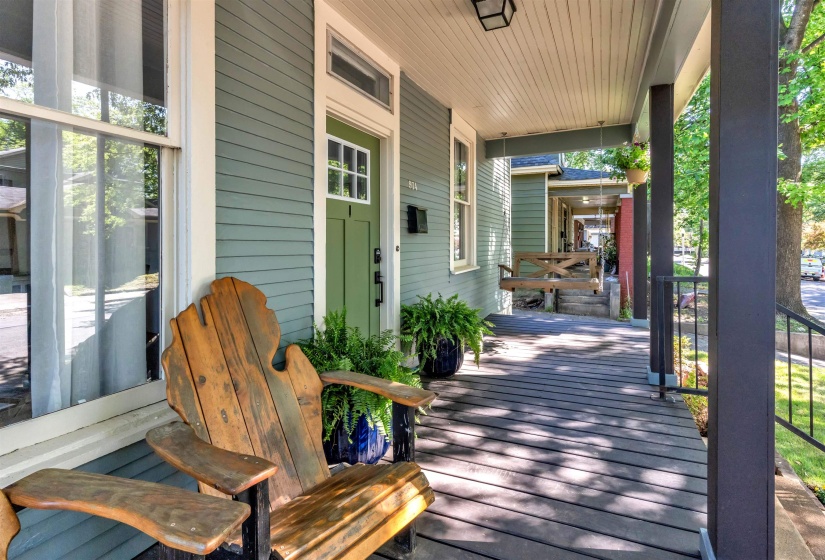 Expansive covered porch featuring wood-finish decking, decorative pillars, and a ceiling-mounted light fixture
