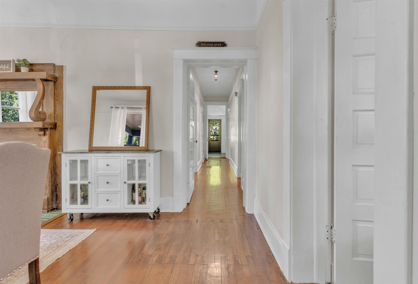Hardwood flooring extends throughout this interior space, featuring a white paneled door with multiple inset rectangles and a detailed wooden mantel