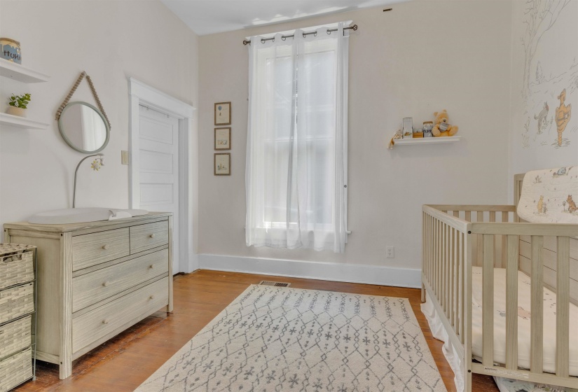 Room featuring wood-finish flooring, a single window with white sheer curtains, and a white paneled interior door