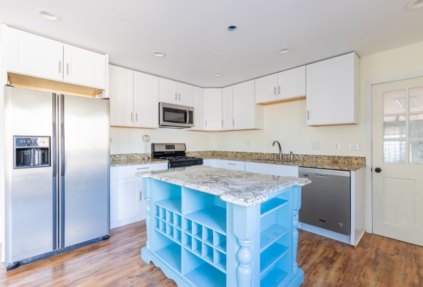 Kitchen featuring appliances with stainless steel finishes, open shelves, light stone countertops, white cabinetry, and dark wood-style floors