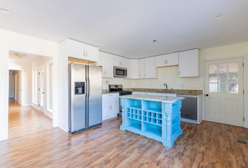 Kitchen with open shelves, stainless steel appliances, white cabinetry, light wood-type flooring, and light stone counters