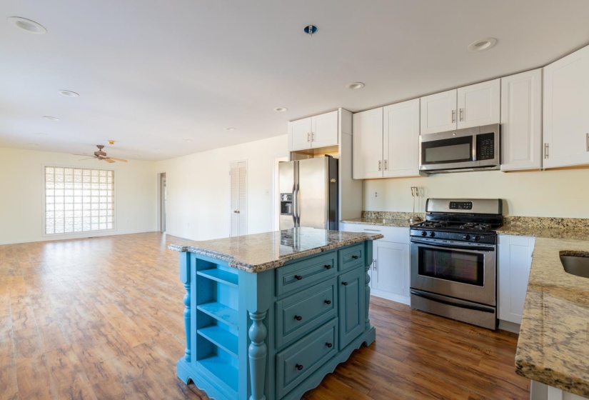 Kitchen featuring open shelves, stainless steel appliances, white cabinets, light stone countertops, and recessed lighting