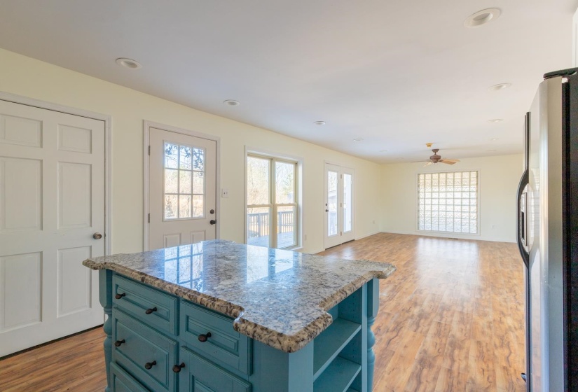 Kitchen featuring blue cabinets, open shelves, freestanding refrigerator, light wood finished floors, and light stone counters