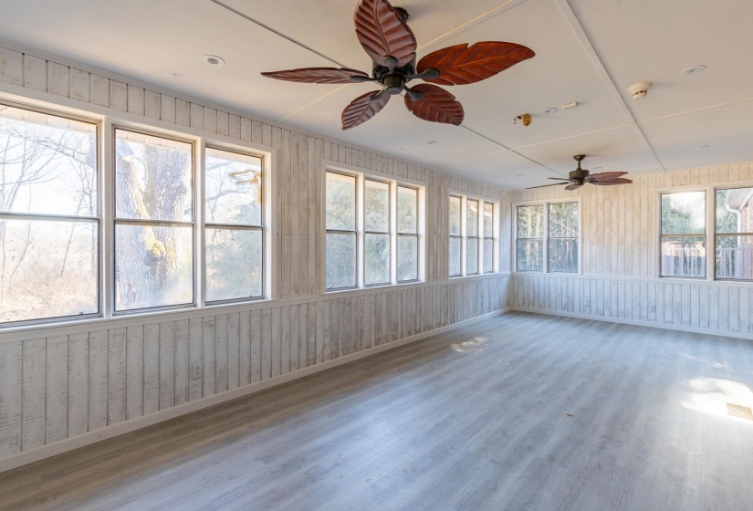 Unfurnished sunroom with wood finished floors and wooden walls