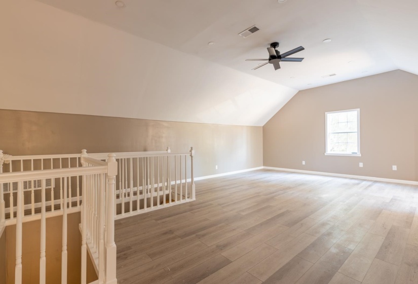Bonus room with vaulted ceiling, light wood-style floors, and ceiling fan