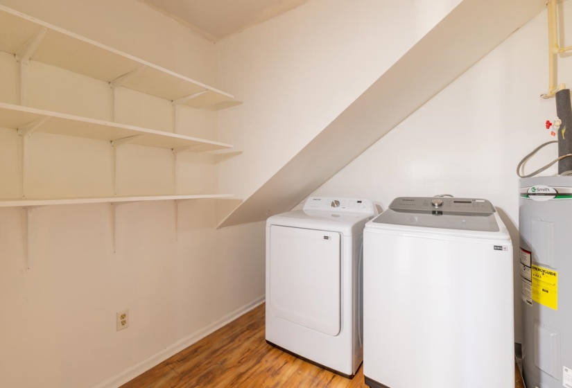 Laundry room featuring water heater, light wood-style flooring, and washer and dryer