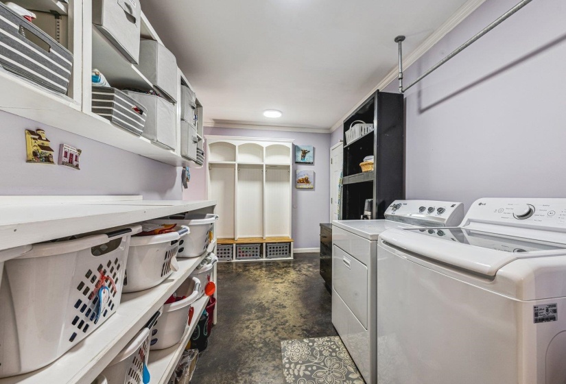 Dedicated laundry area featuring white appliances, a built-in hanging rod, and extensive shelving