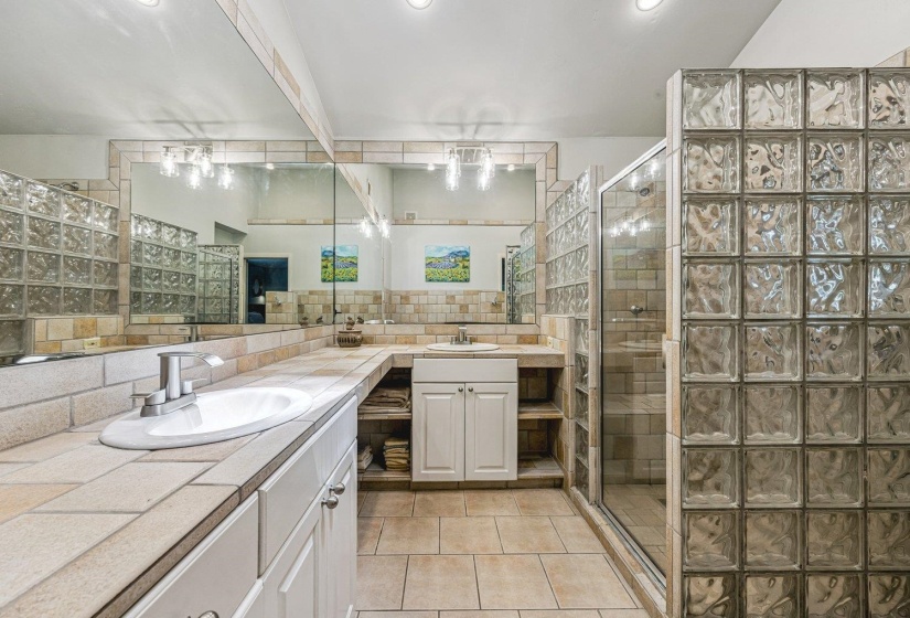 Bathroom featuring a glass block shower enclosure and a double vanity with integrated sinks